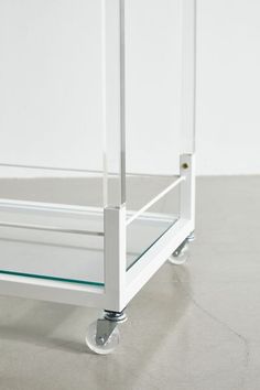 a white cart with glass shelves on wheels