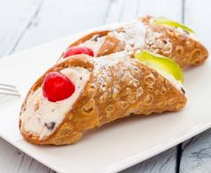 two croissants with cherries and cream on them are sitting on a white plate