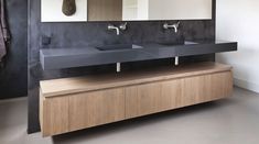 a bathroom with two sinks and mirrors on the wall next to a wooden cabinet in front of it