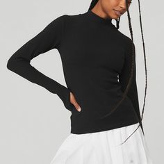 Wellness Rib Mock Neck Long Sleeve - Black | Alo Yoga High Stretch Tops With Thumbholes For Winter, High Stretch Winter Tops With Thumbholes, Winter Tops With Thumbholes And High Stretch, Ribbed Stretch Mock Neck Top With Long Sleeves, Ribbed Mock Neck Top With Long Sleeves, Versatile Funnel Neck Top With Ribbed Cuffs, Spring Ribbed Mock Neck Top For Layering, Versatile Ribbed Turtleneck Tops, Sleek Black Mock Neck Top For Fall