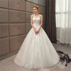 a woman in a white wedding dress standing next to a wall with a mirror behind her