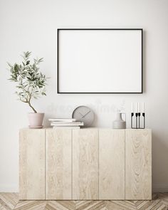 an empty frame on the wall above a wooden cabinet with plants and vases in it