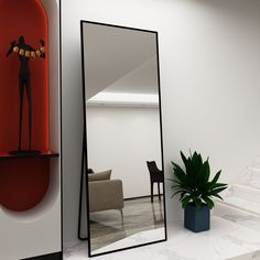 a mirror sitting on top of a white counter next to a chair and potted plant