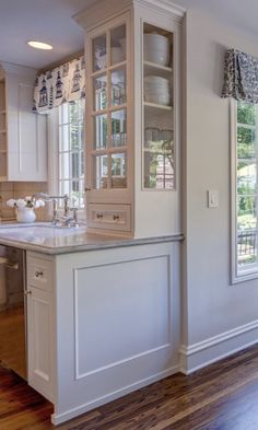 a kitchen with white cabinets and wood floors in the middle of an open floor plan