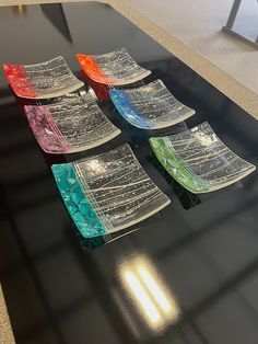 five pieces of glass sitting on top of a black table in front of a window