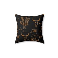 a black and gold pillow with an image of a cactus, longhorns, and other animals on it