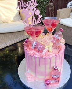 a cake with pink frosting and two martini glasses on top, sitting on a table