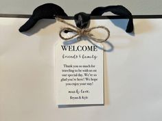 a welcome sign hanging on the wall with a ribbon attached to it's back