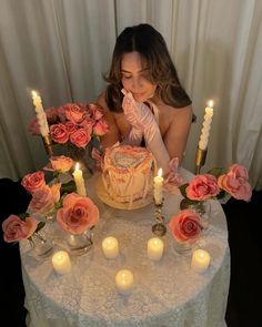 a woman sitting at a table with a cake and candles in front of her face