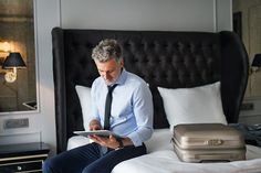 a man sitting on top of a bed holding a tablet