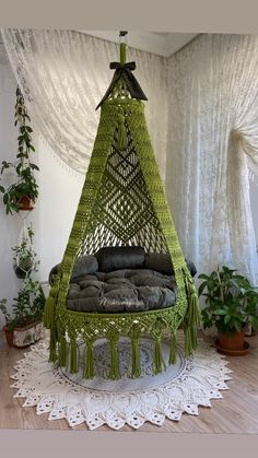 a green hammock hanging from the ceiling in a room with potted plants