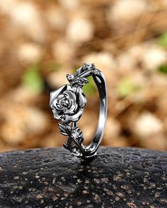 a silver rose ring sitting on top of a rock