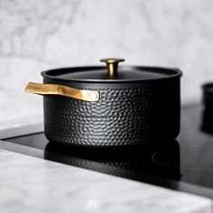 a pot sitting on top of a stove next to a burner with a gold handle