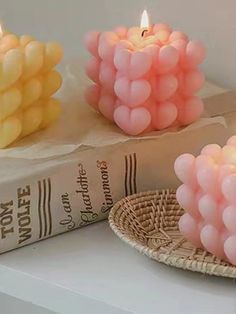 three candles sitting on top of a table next to a book and basket filled with balloons