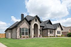 a large brick house sitting on top of a lush green field