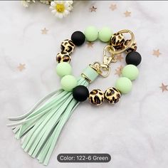 the green and black bracelet with leopard print beads is on top of a white table