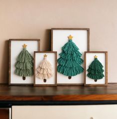 three framed christmas trees are displayed on a shelf