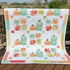 a quilted table topper on a wooden deck with an autumn scene in the background