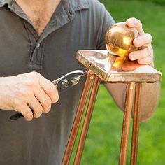 a man is using a pair of scissors to trim a piece of copper on an easel