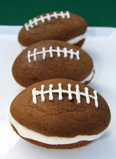 three chocolate football cookies sitting on top of a white plate