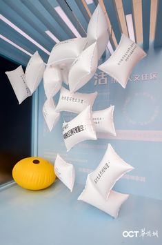 a bunch of white paper flying in the air next to a yellow ball on a table