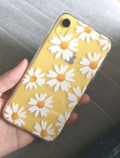 a person holding an iphone case with white daisies on the front and yellow back