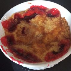 a white bowl filled with food on top of a black counter next to a knife and fork