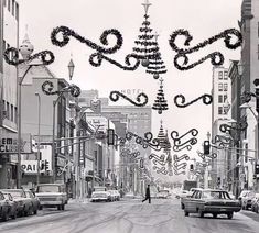 a black and white photo of a city street decorated for christmas