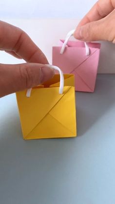 a hand is holding an origami envelope in front of the other paper bag