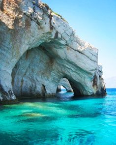 the water is crystal blue and there is a rock formation in the middle of it