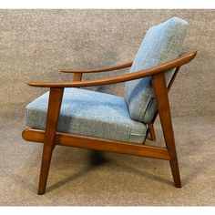 a wooden chair with a blue upholstered seat and back cushion on carpeted floor