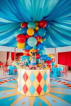 balloons are floating in the air above a table with blue, yellow and red decorations