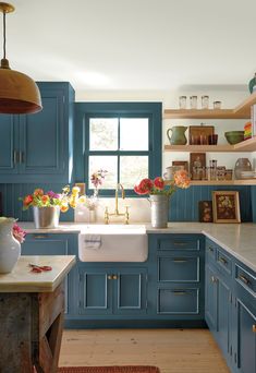 a kitchen filled with lots of blue cabinets and counter top space next to a window