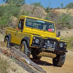 a yellow truck driving down a dirt road