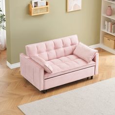 a pink couch sitting on top of a hard wood floor next to a white rug