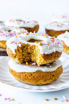 carrot cake donuts with white frosting and sprinkles on a plate