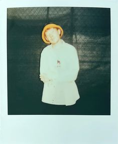 a polaroid photograph of a person wearing a white coat and yellow hat with his arms crossed