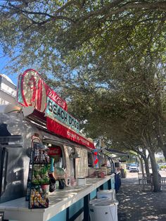 the food truck is parked on the side of the road next to some trees and trash cans