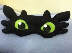 a black cat with green eyes laying on top of a bed