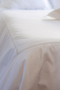 an unmade bed with white sheets and pillows