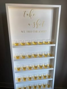 there is a display case filled with small glasses and bottles in front of a sign that says take a shot we tied the knot