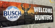 a welcome sign is hanging on the side of a building in front of an advertisement for busch light