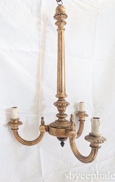 an antique chandelier with three candles hanging from it