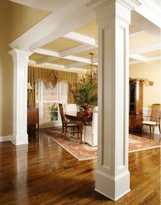 an open living room with wooden floors and white columns