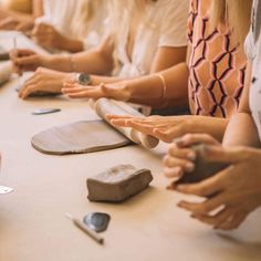 a group of people sitting at a table with their hands together