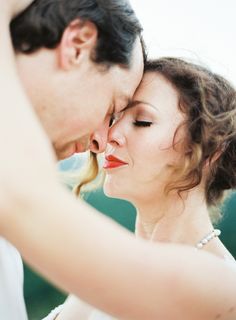 a bride and groom pose for a wedding photo in front of the camera with their eyes closed