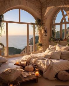 a bedroom with an arched window overlooking the ocean and candles on the table in front of it