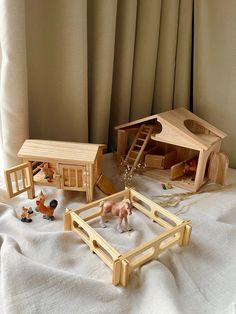 wooden toys are laying on a bed with white sheets and drapes in the background