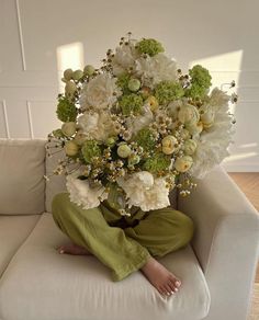 a person sitting on a couch with a bouquet of flowers in front of their face