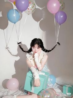 a woman sitting on top of a bed next to balloons